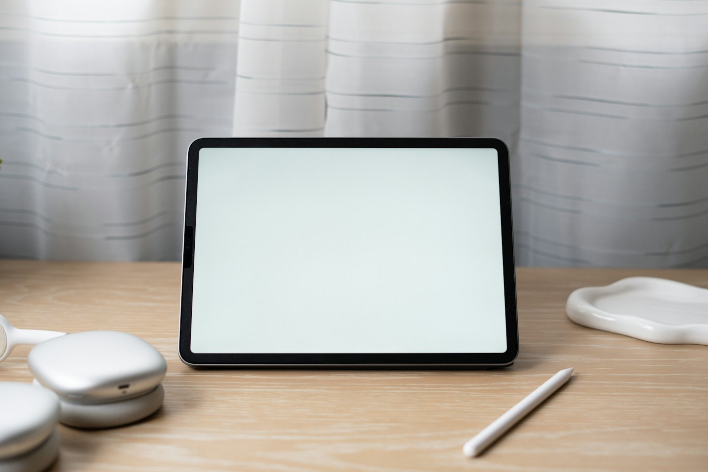 Tablet s prázdnou obrazovkou a slúchadlami na stole.
